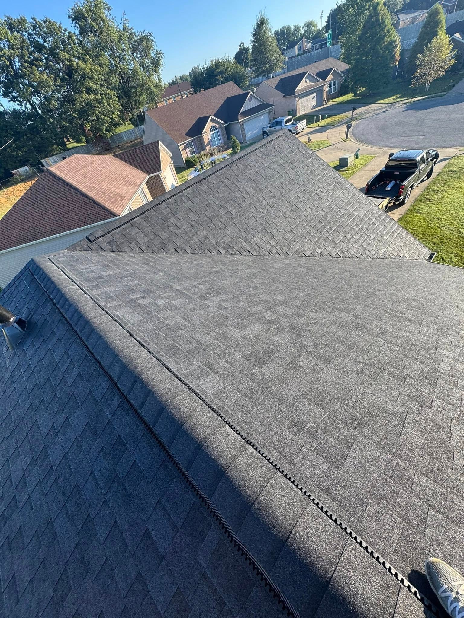View from a gray shingled rooftop over a suburban neighborhood on a sunny day