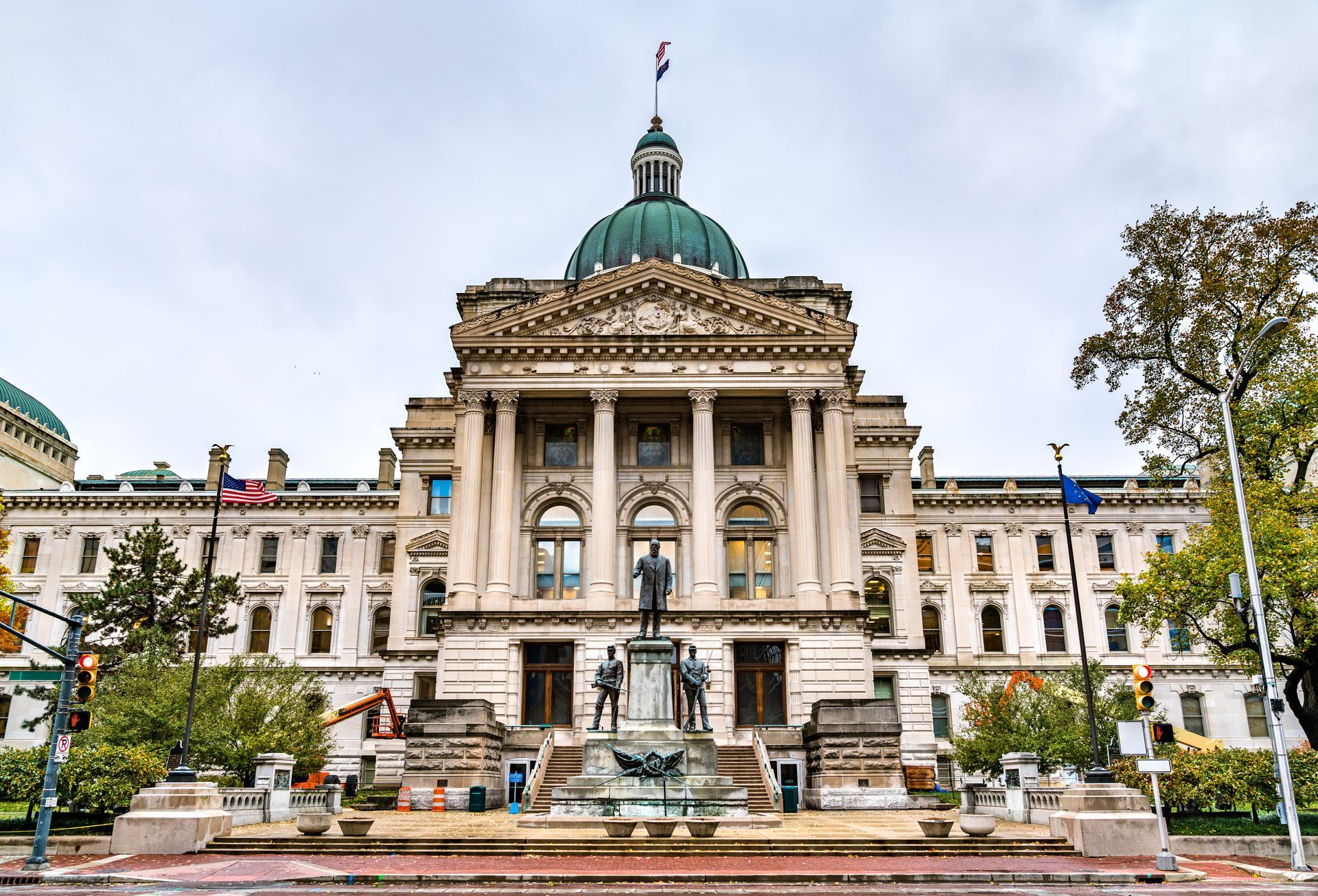 Grand neoclassical building with a green dome and fountain in front, viewed from a landscaped plaza