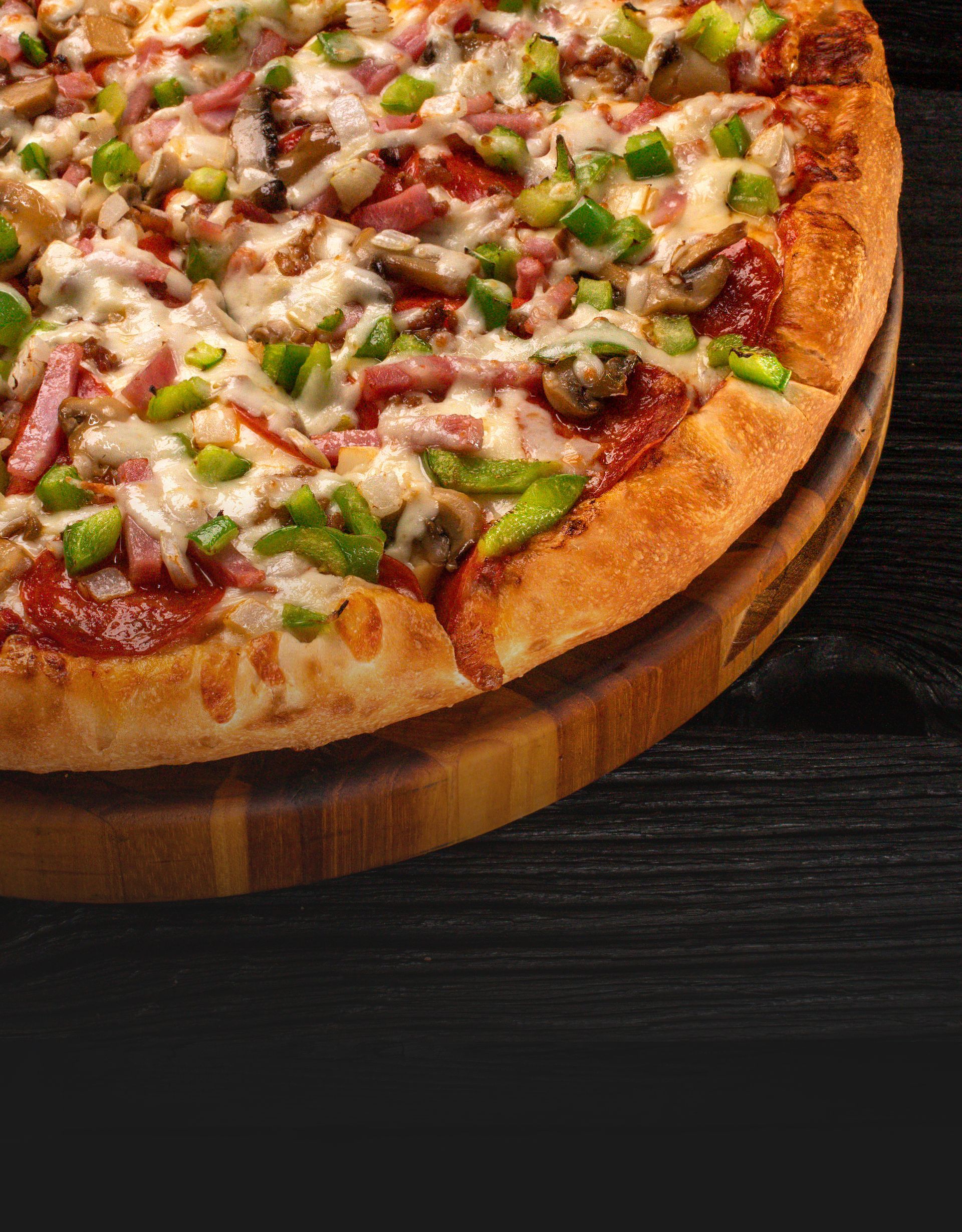Close up of an everything pepperoni pizza with green peppers and ham