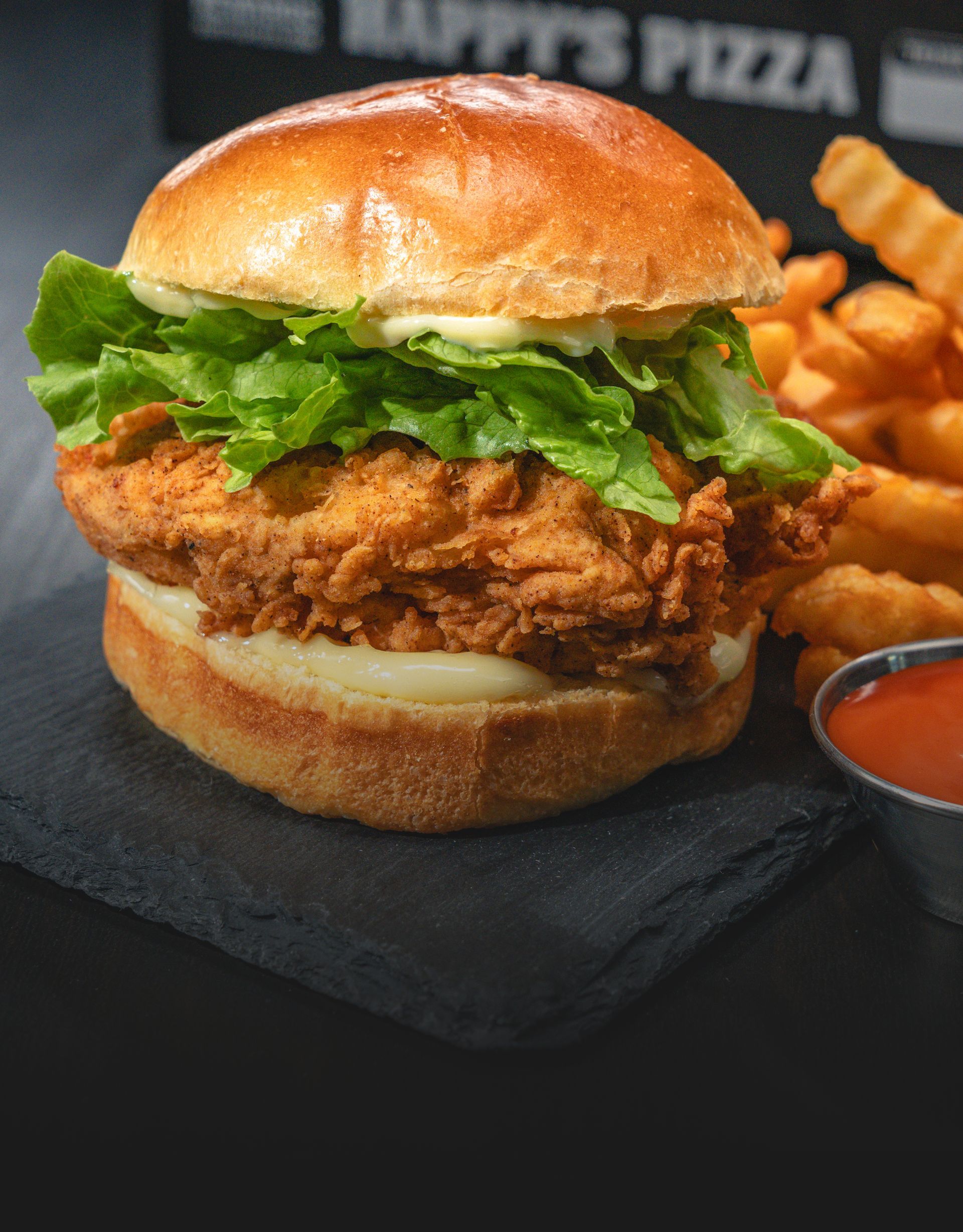 Crispy fried chicken sandwich topped with lettuce and served with crinkle fries and dipping sauce.