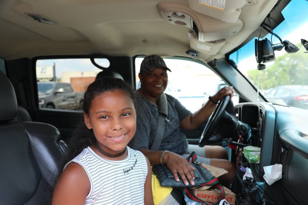 A man and a little girl are sitting in the back seat of a car.