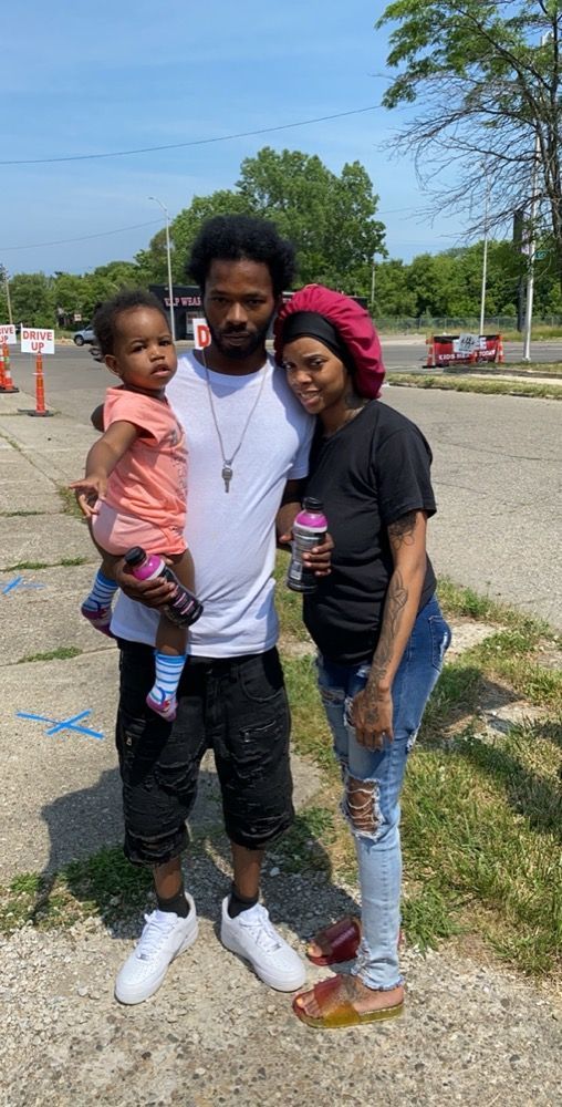 A man and woman are standing next to each other holding a baby.