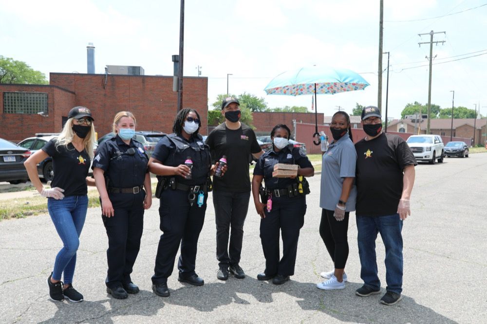 A group of people wearing masks are standing next to each other in a parking lot.