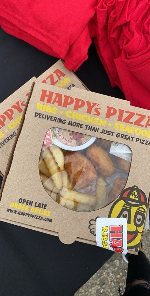 Two boxes of happy 's pizza are sitting on a table.