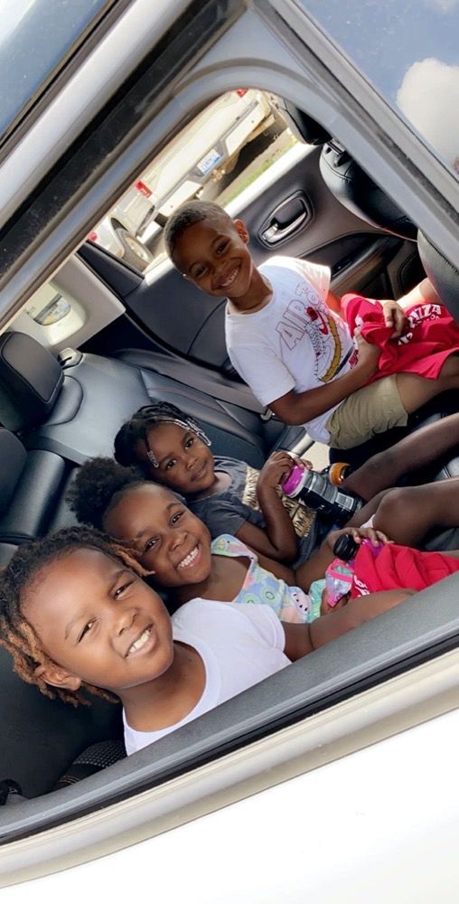 A group of children are sitting in the back seat of a car.