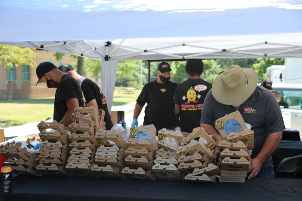 A group of men are preparing food under a tent.