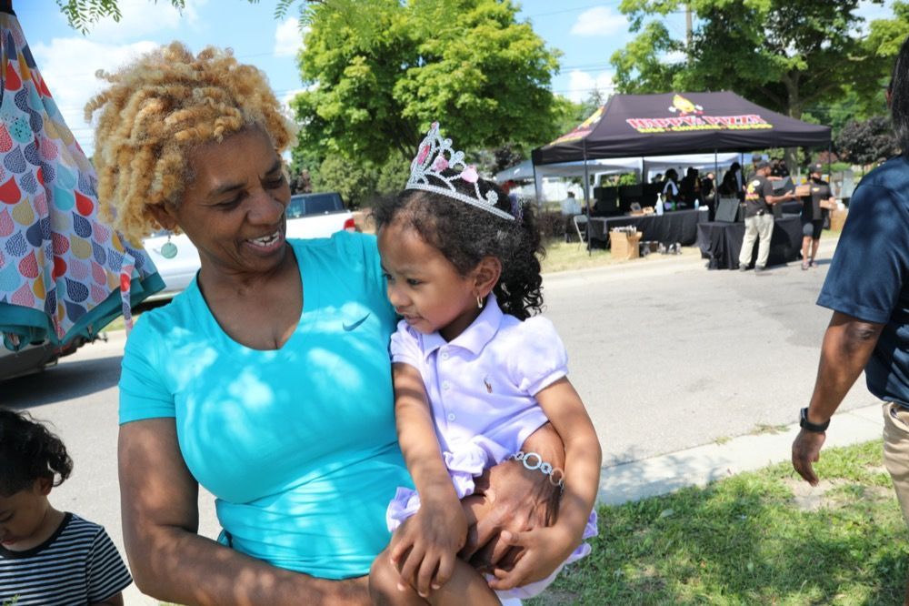 A woman is holding a little girl wearing a tiara.