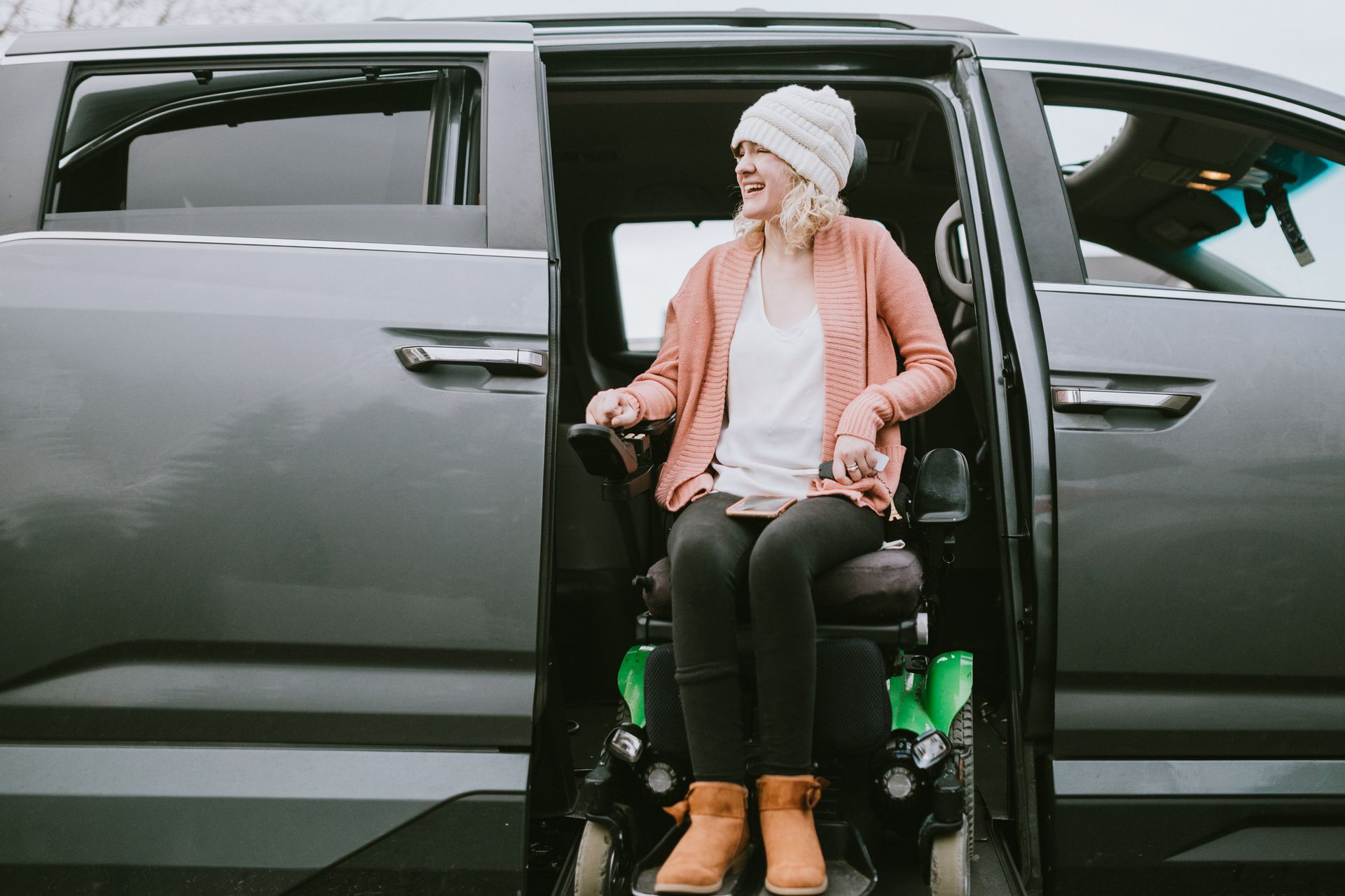A woman in a wheelchair is getting out of a van.
