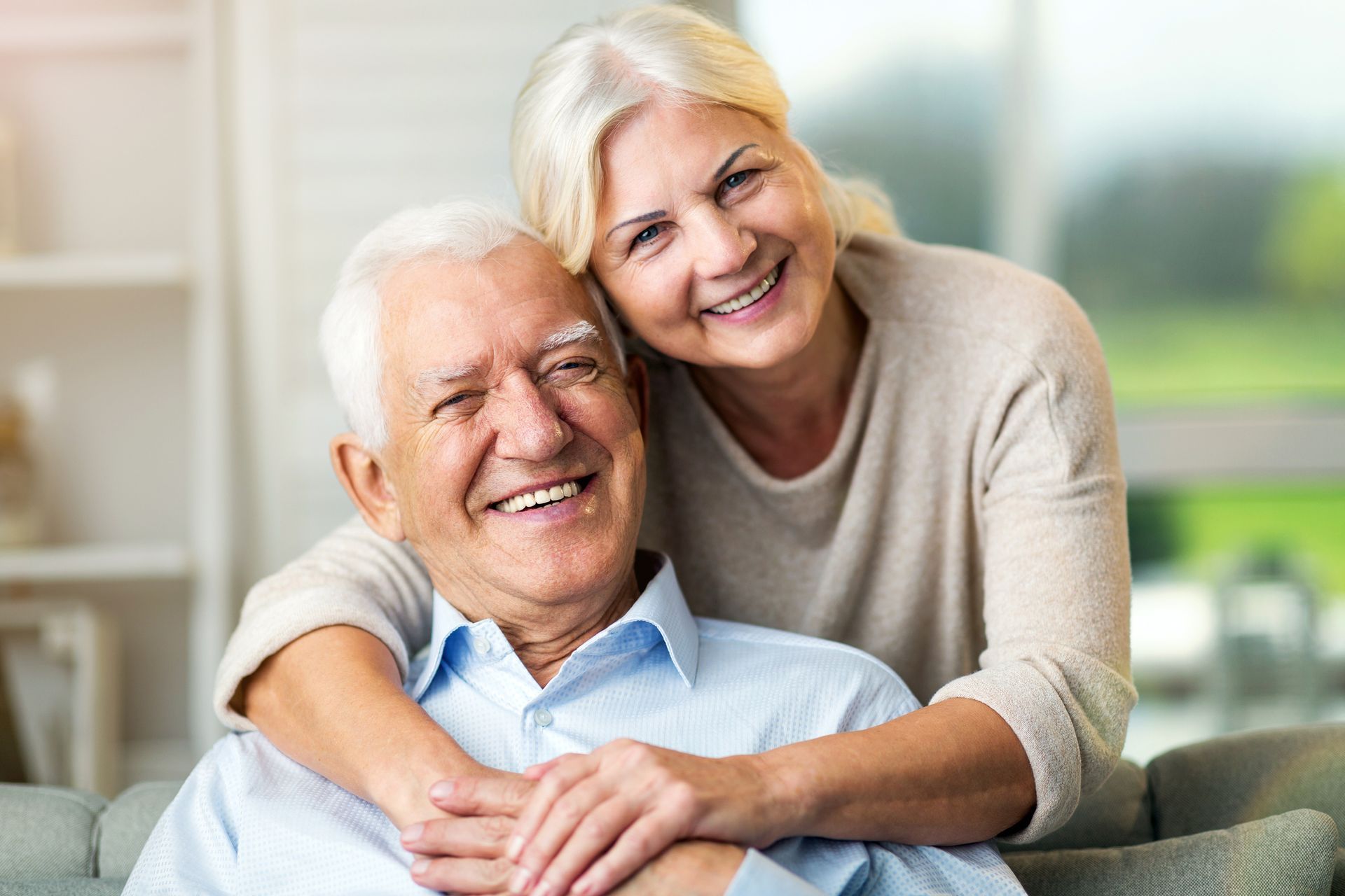 A woman is hugging an older man on a couch.