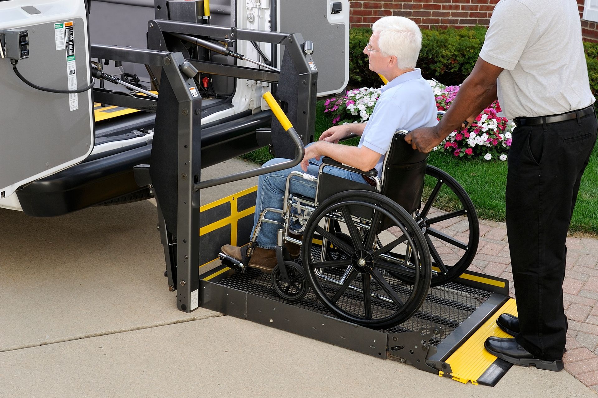 A man in a wheelchair is being lifted into a van
