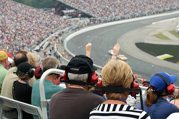 A group of people are sitting in a stadium watching a race.