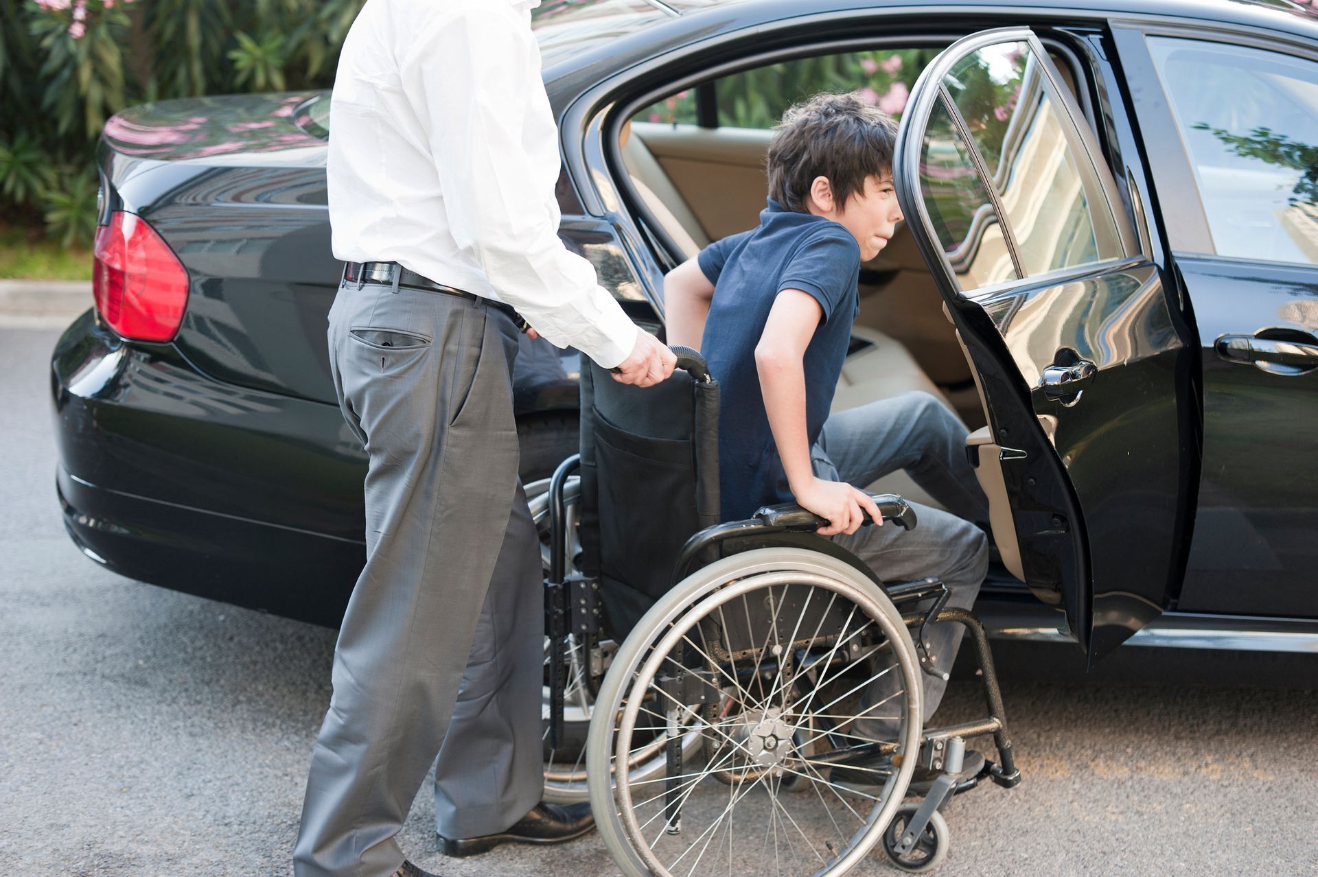 A man pushing a man in a wheelchair into a car