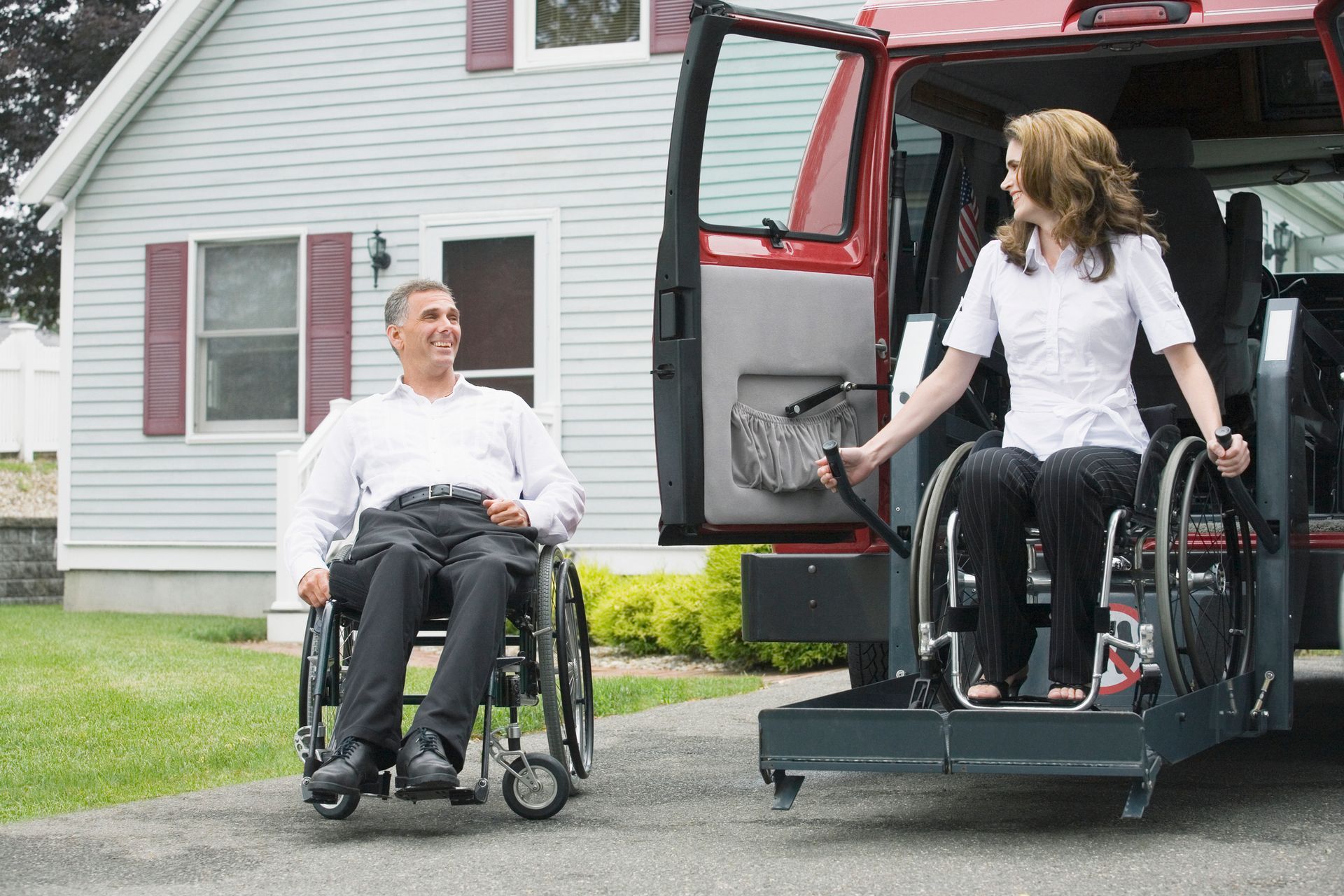 A man in a wheelchair and a woman in a wheelchair are getting out of a van.