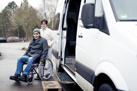 A man in a wheelchair is getting out of a van.