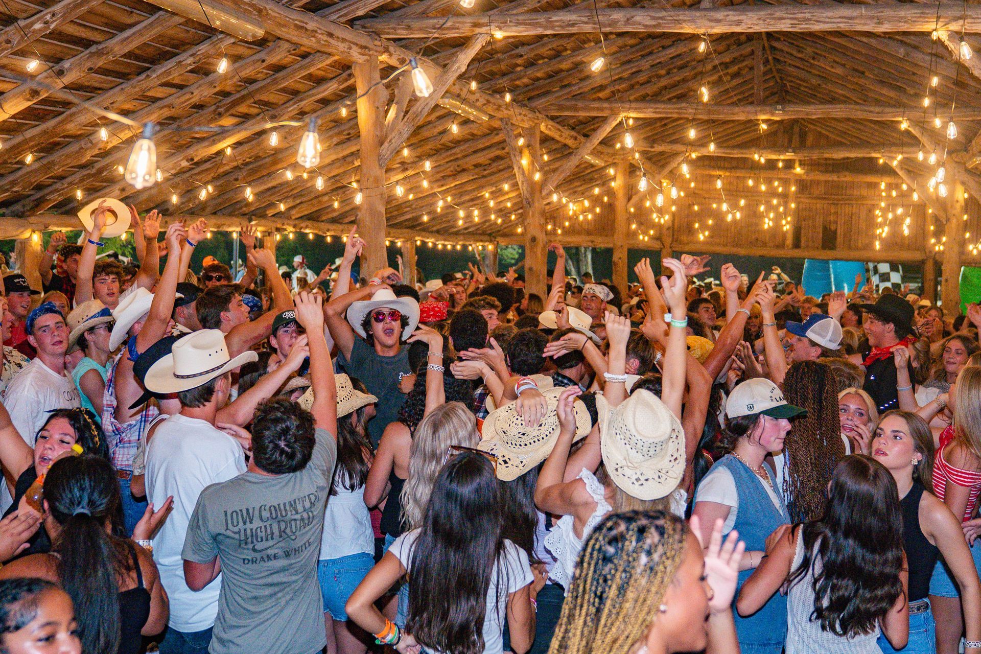 Crowd dancing and cheering under string lights at a lively indoor party