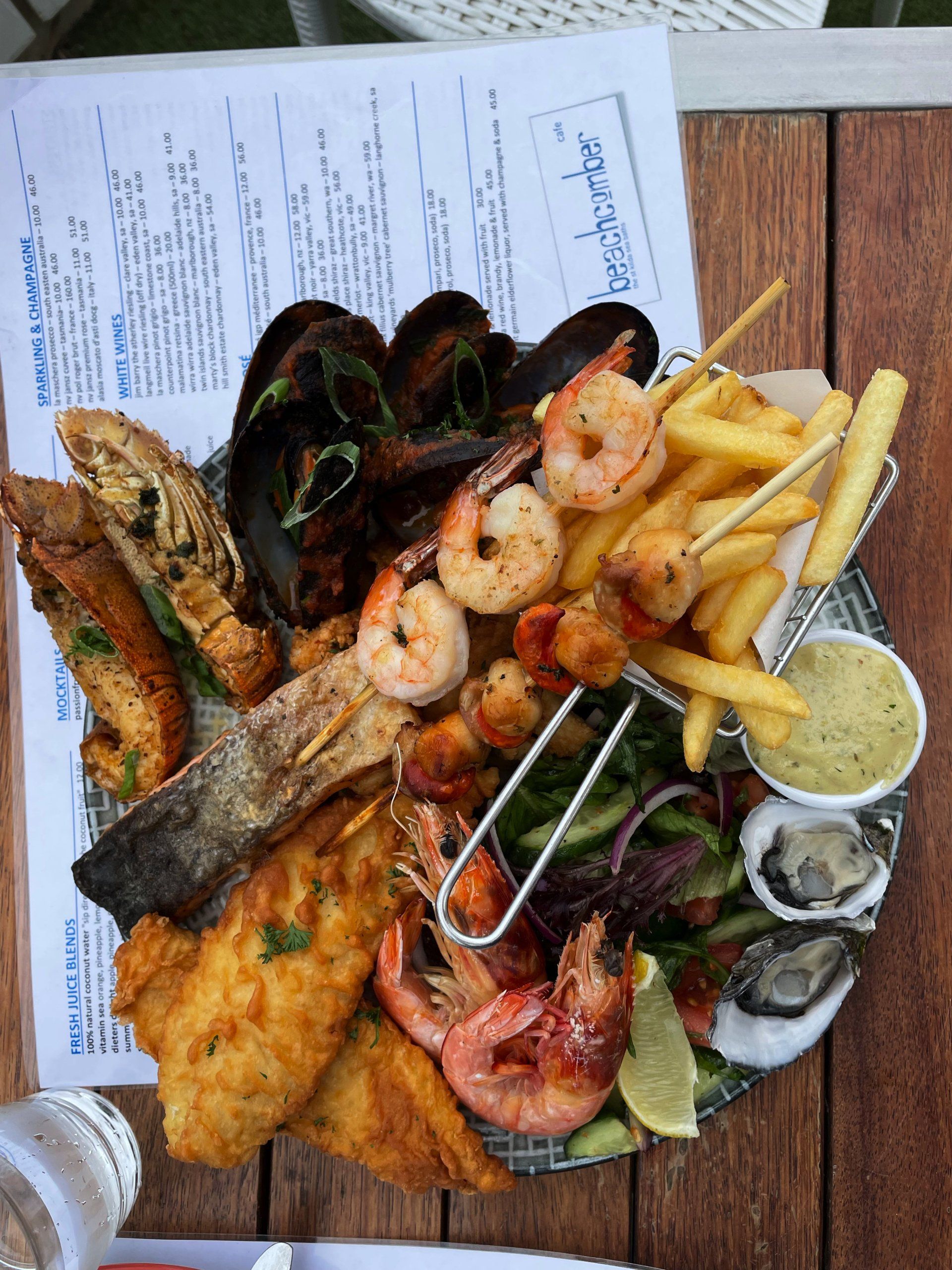 A plate of seafood and french fries on a wooden table.