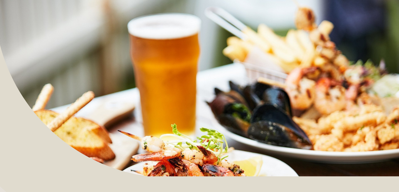 A table topped with plates of food and a glass of beer.