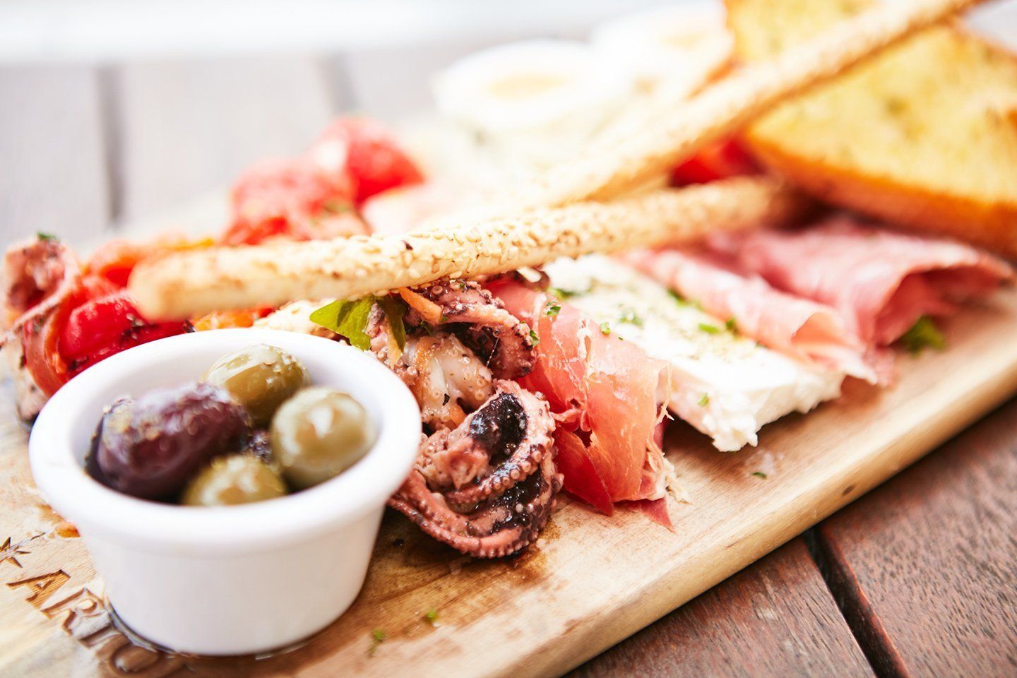 A wooden cutting board topped with a variety of meats and vegetables.