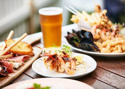 A table topped with plates of food and a glass of beer.