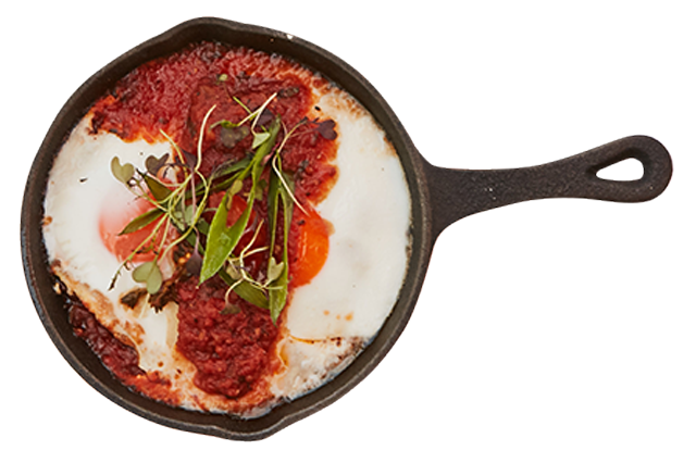 A skillet filled with eggs and sauce on a white background