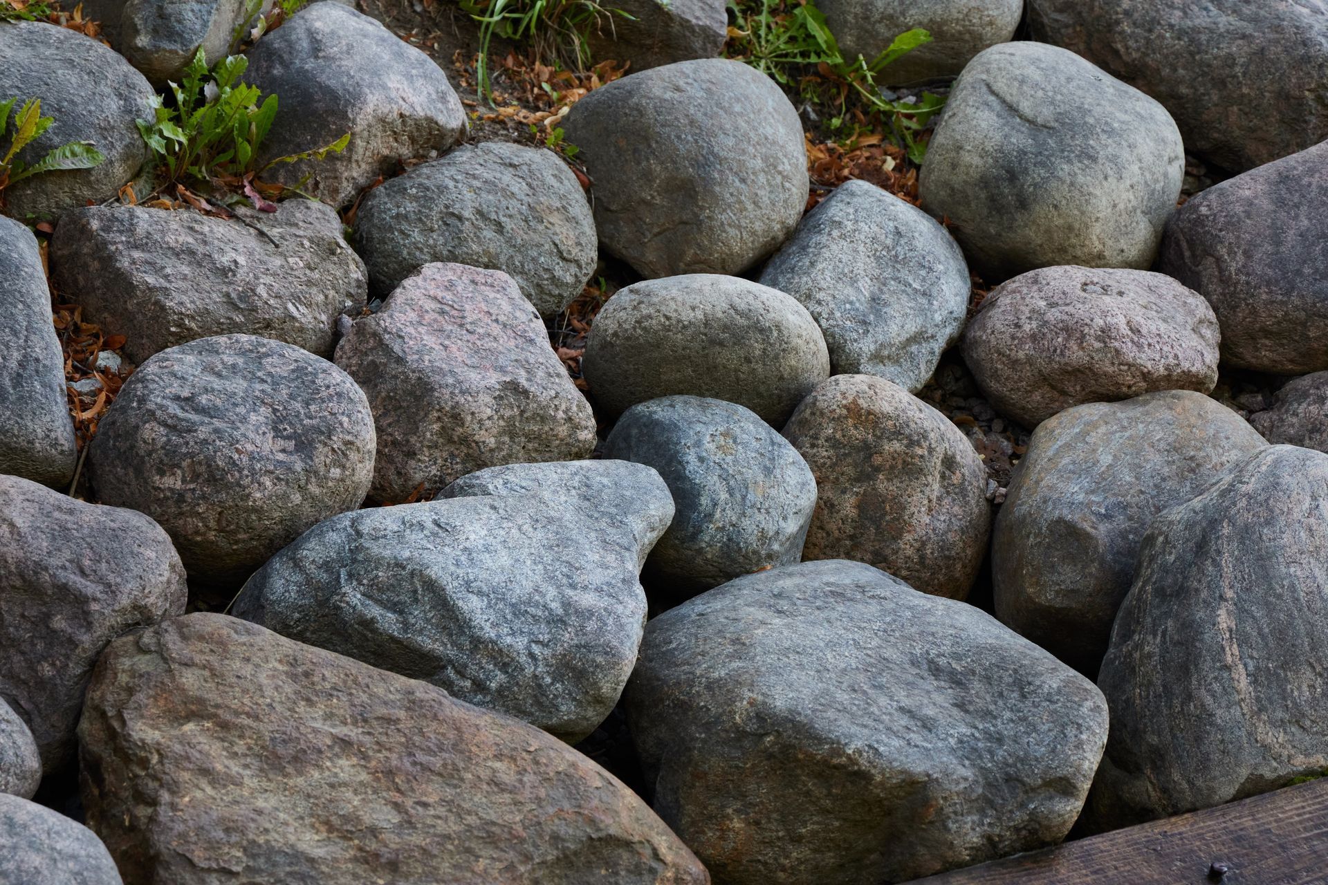 Close-up of smooth gray and brown rocks with patches of green moss and grass