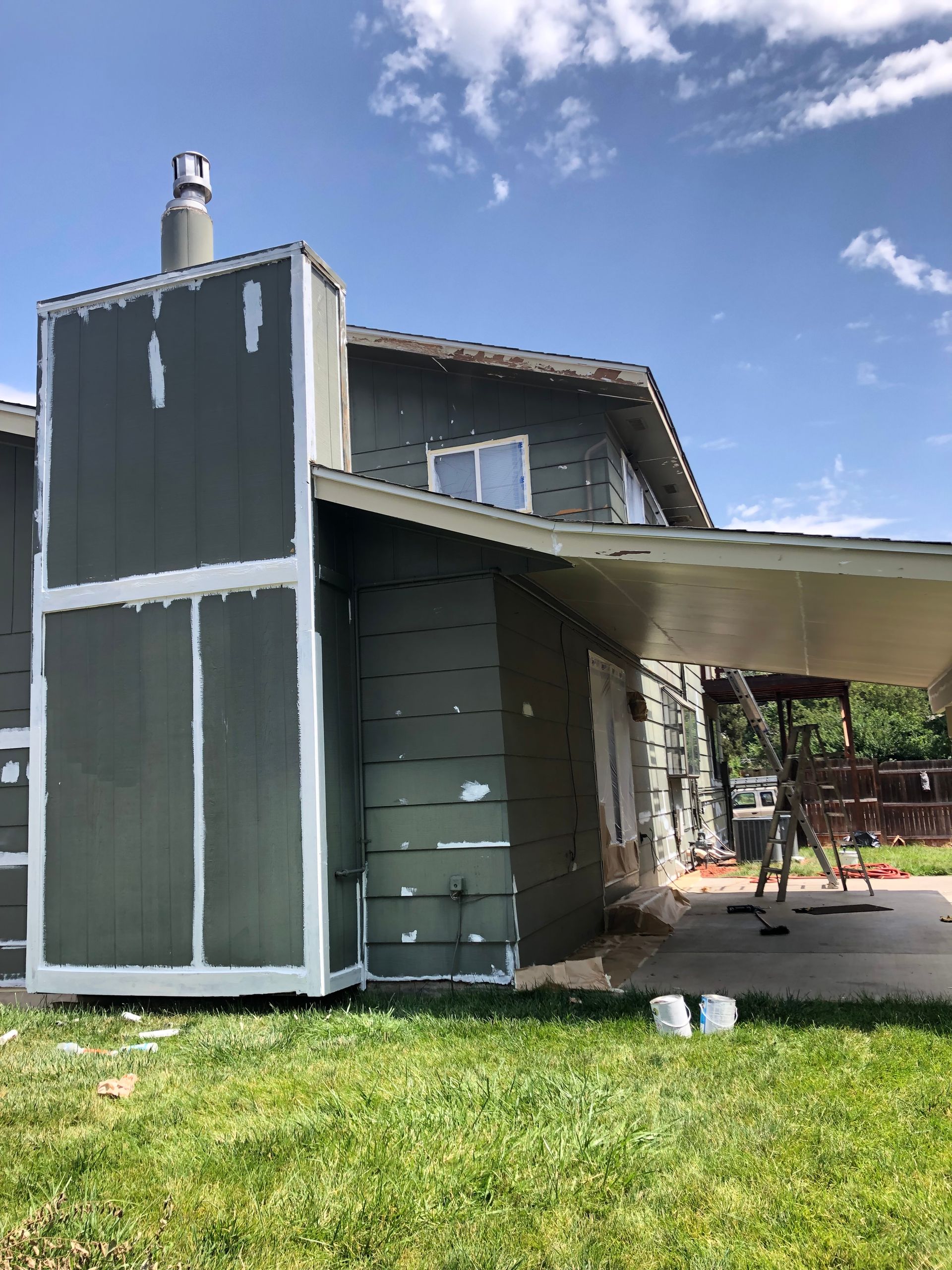 A House Is Being Painted In A Yard With A Blue Sky In The Background