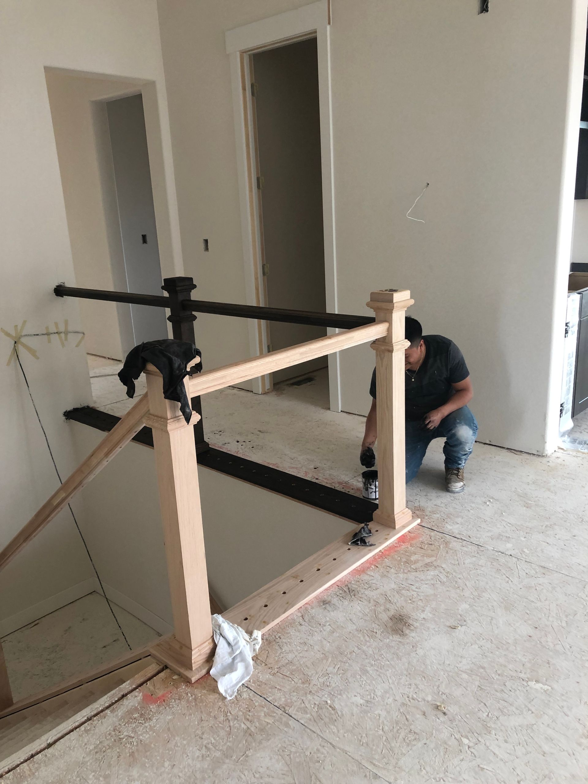A Man Is Kneeling Down Next To A Wooden Railing In A Room