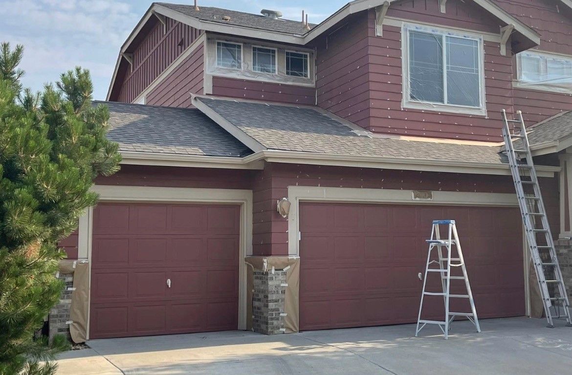 A Large Red House Is Being Painted With A Ladder In Front Of It