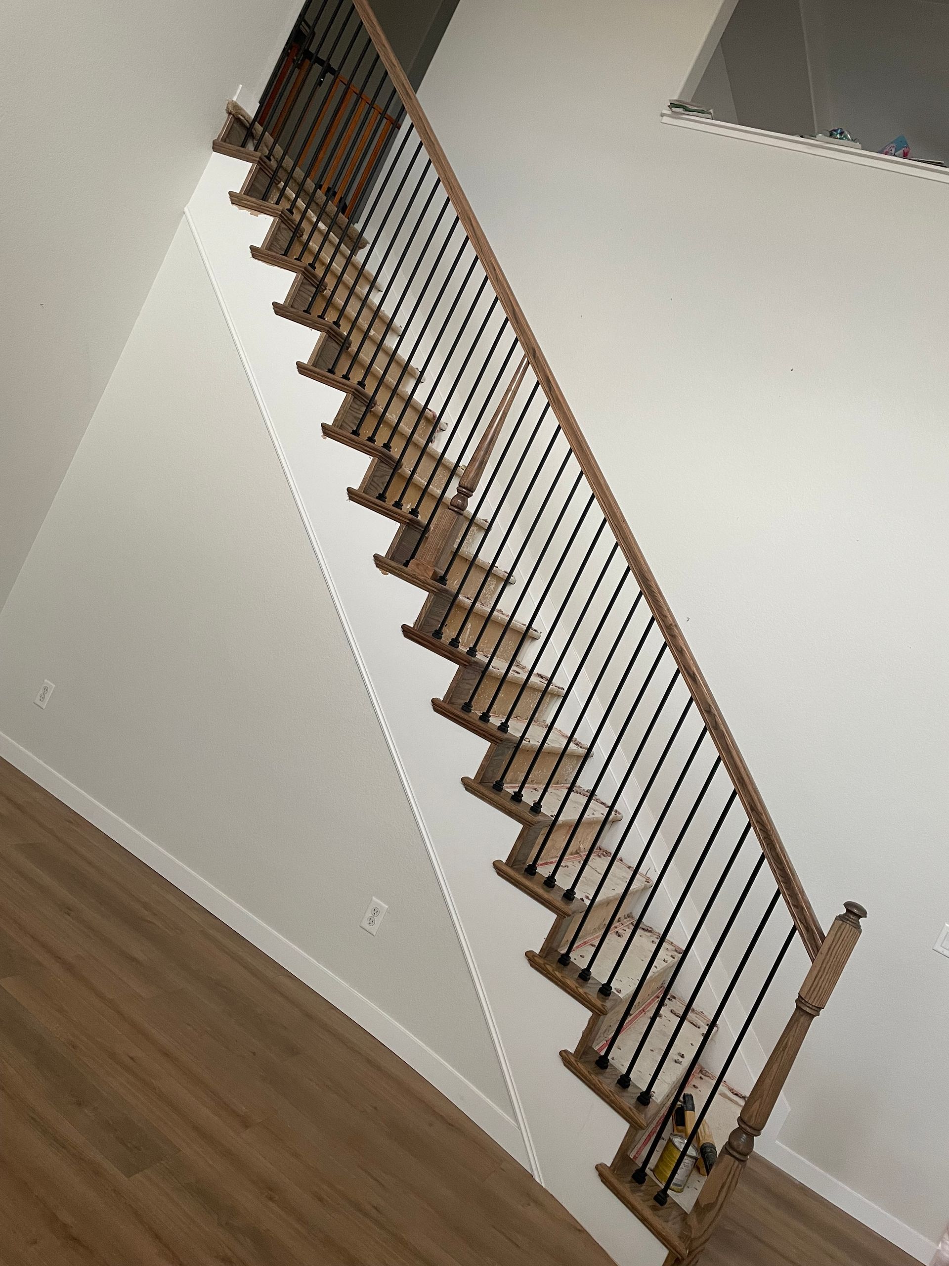 A Wooden Staircase With A Metal Railing In An Empty Room