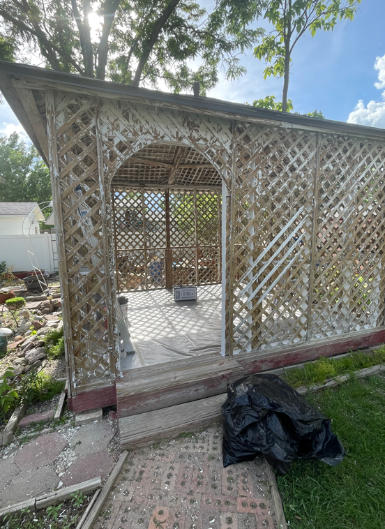 A Wooden Gazebo Is Sitting In The Middle Of A Backyard