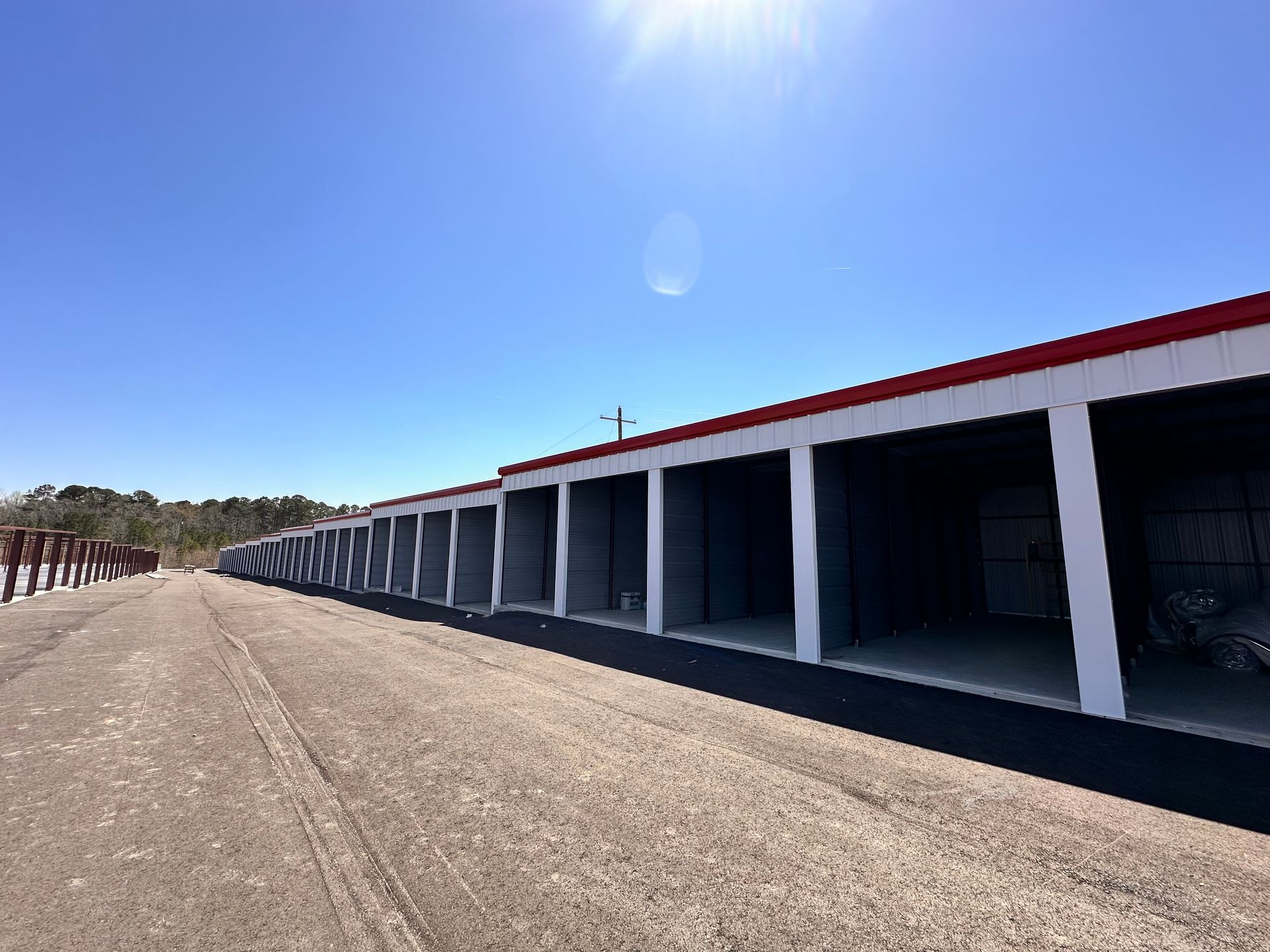Long row of white storage units with red trim under a bright blue sky