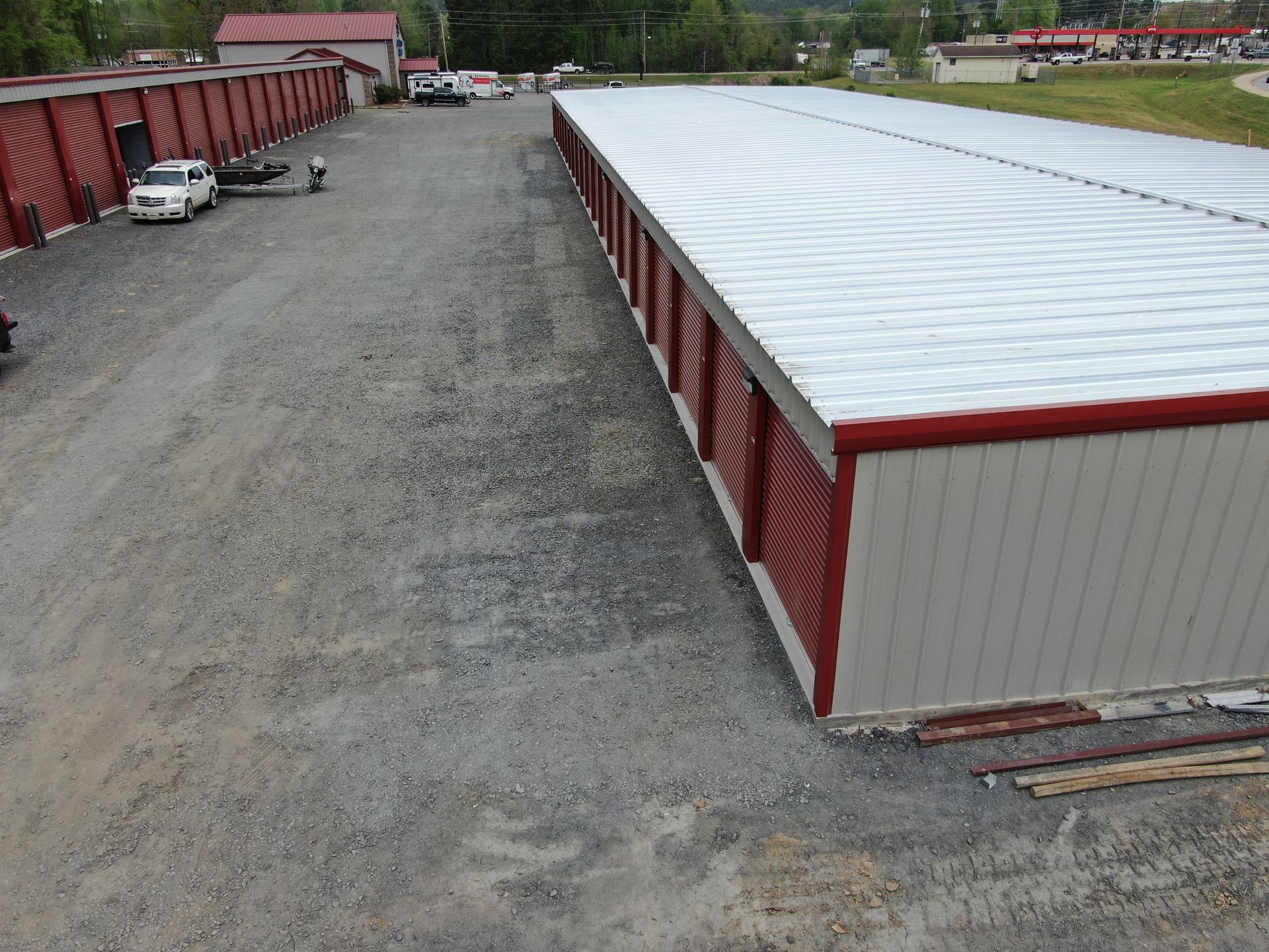 Aerial view of long white-roofed storage buildings with red sides along a gravel lot