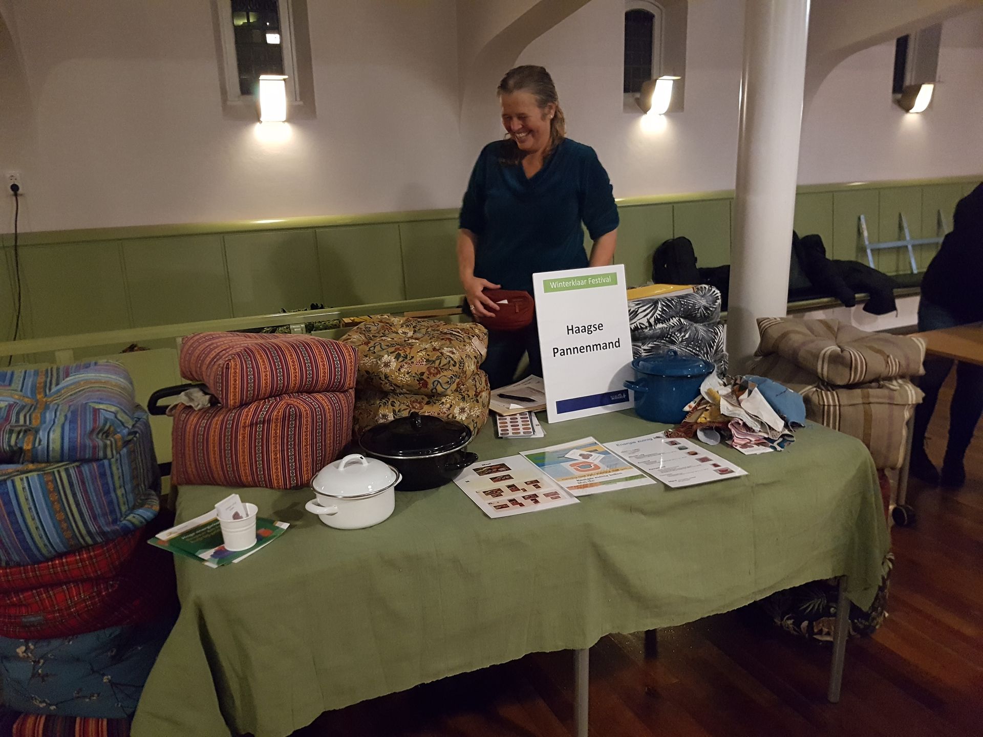 Een kraam met quilts, manden en een bord op een overdekte ambachtsmarkt.