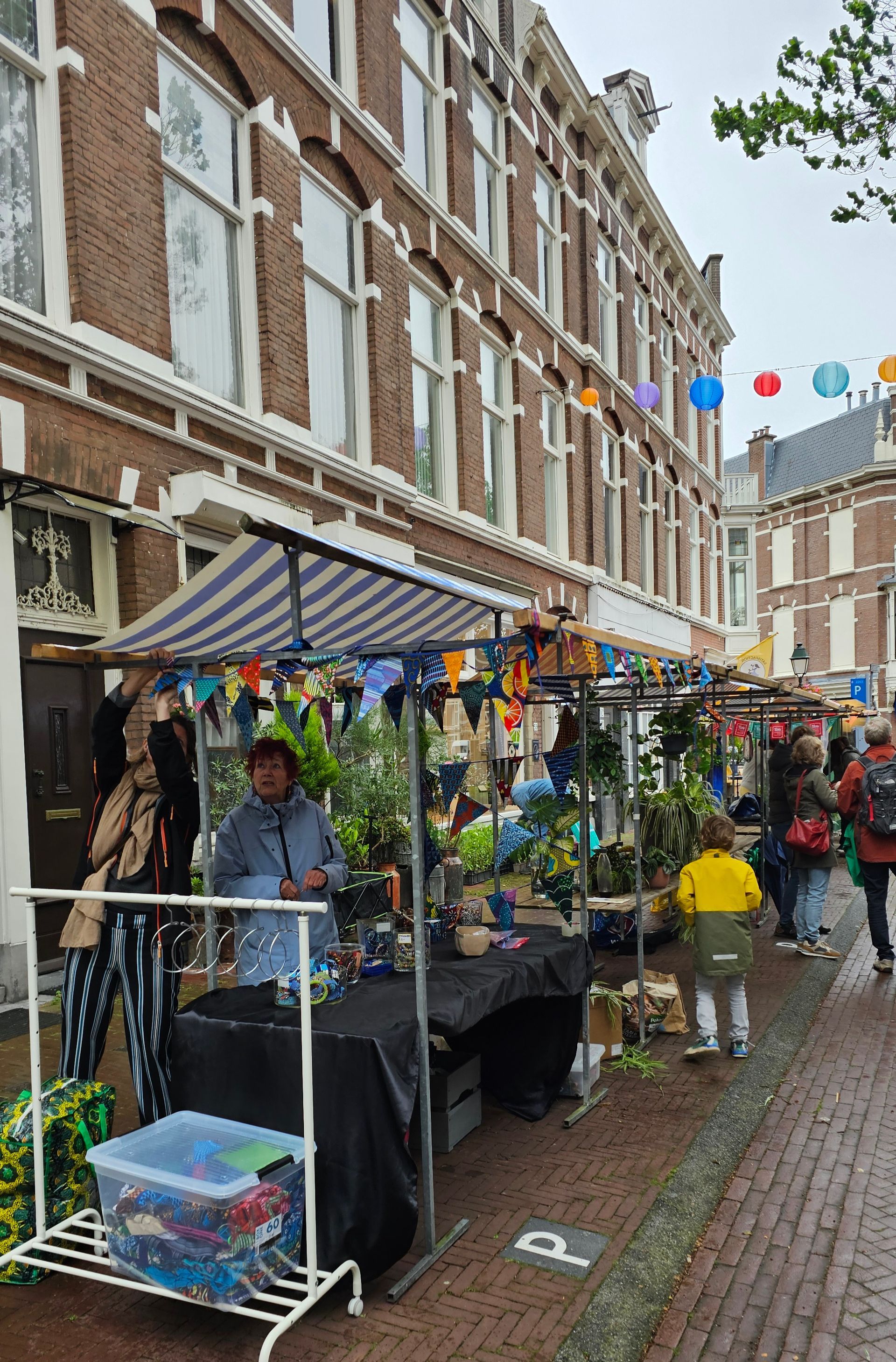 Straatmarktstalletjes met kleurrijke versieringen langs een met bakstenen bestrate steeg naast hoge gebouwen.