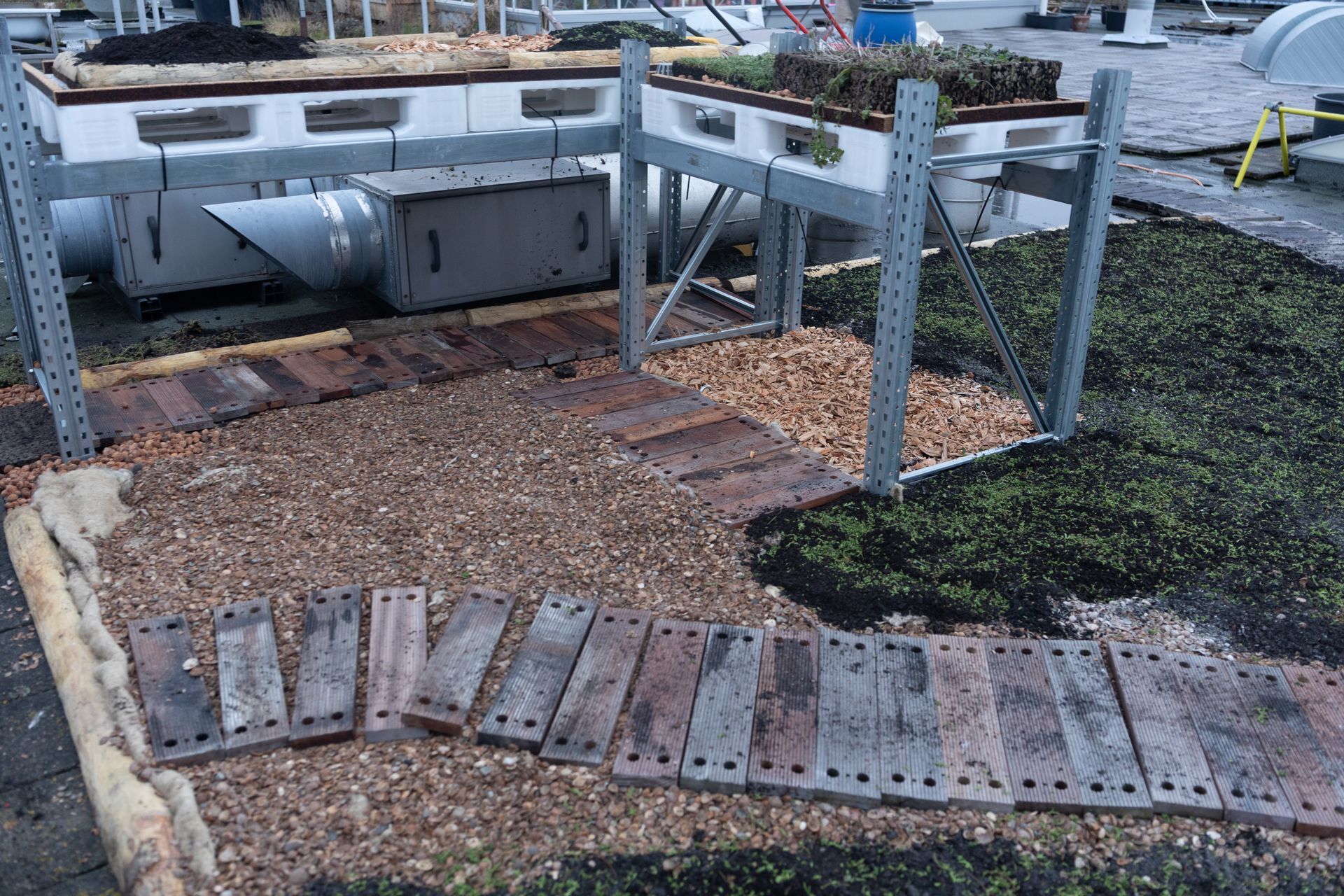 Beschadigde houten vlonder met verspreide planken en een metalen frame nabij een waterkant.