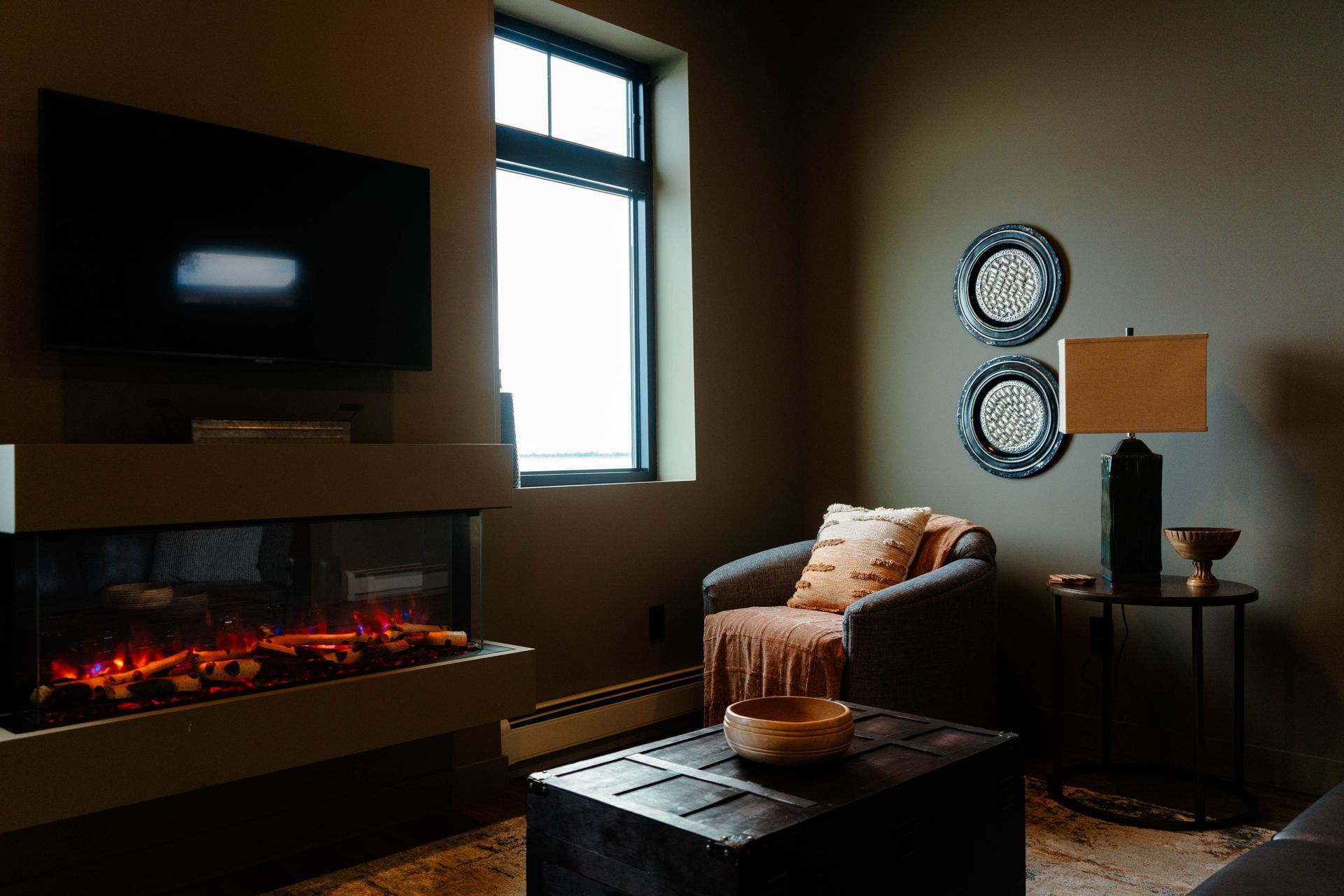 Cozy living room with wall-mounted TV, electric fireplace, armchair, side table, and floor lamp