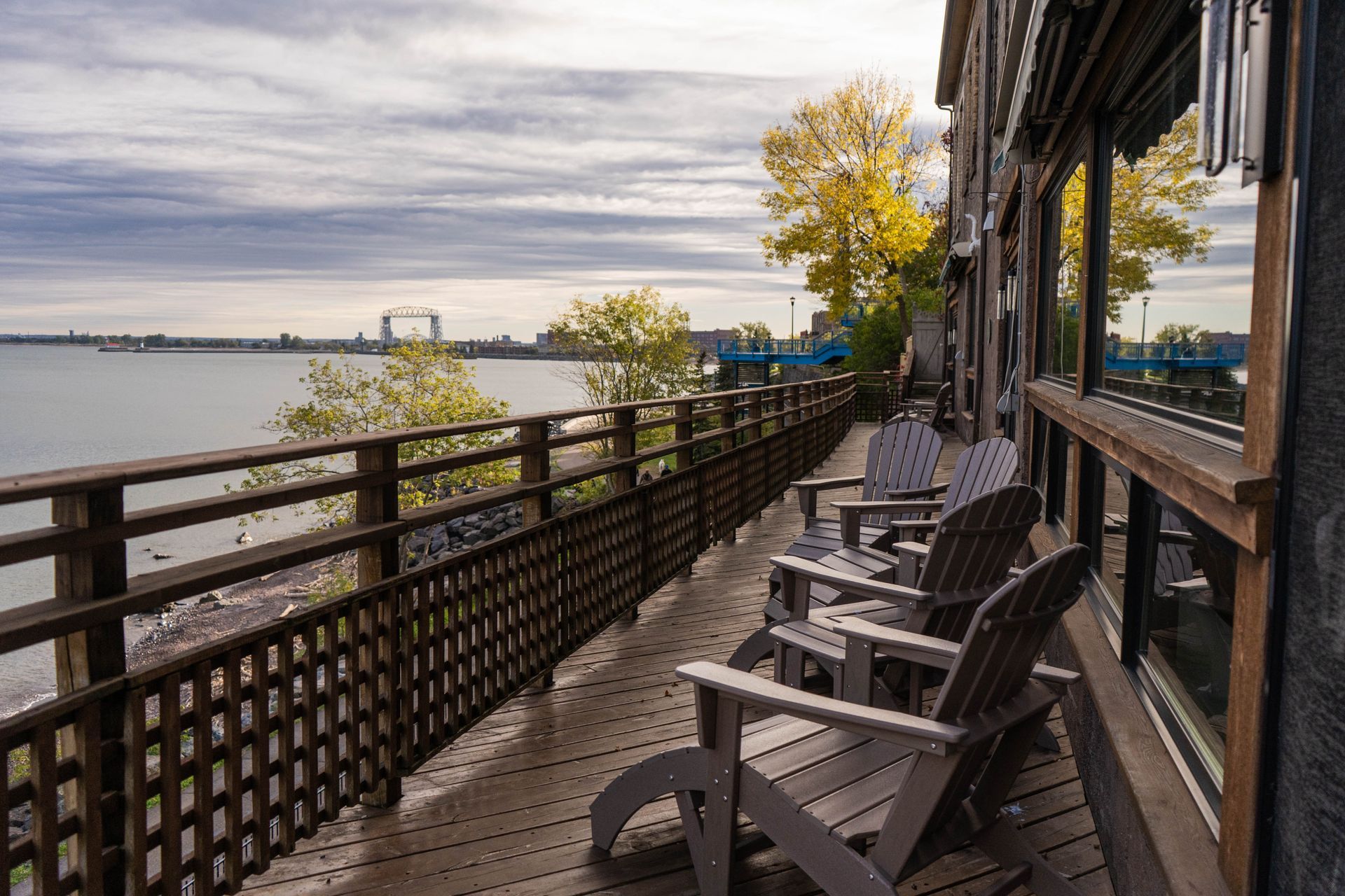 Riverside deck with chairs beside a calm lake under a cloudy sky