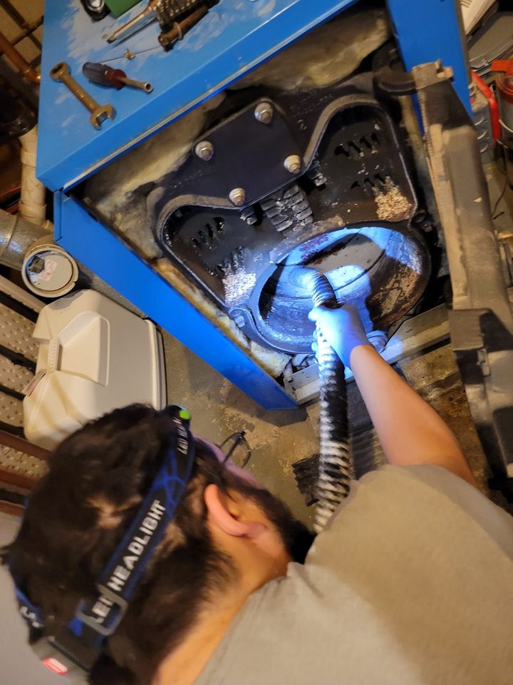 A man wearing a headlight is working on a machine.