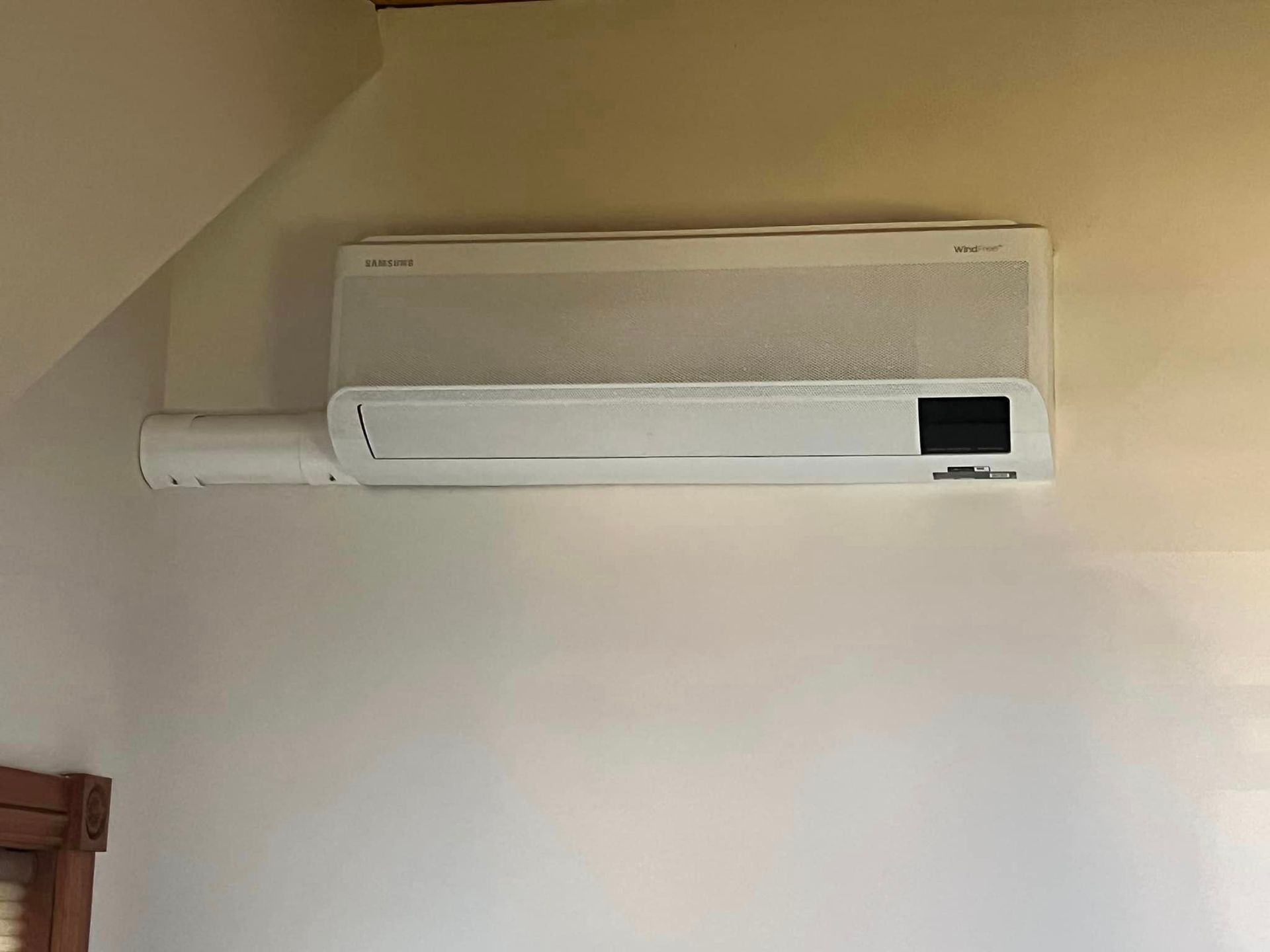 A white air conditioner is sitting on the side of a brick building.
