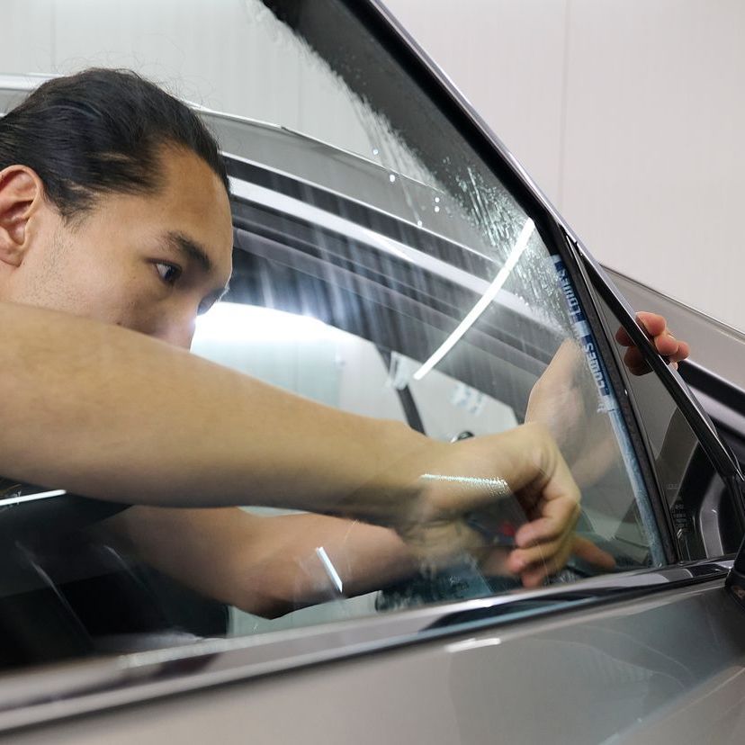 A man wearing a watch is cleaning the fender of a car.