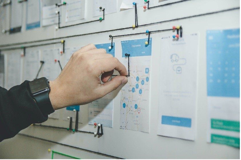 A person is pinning a piece of paper to a whiteboard.
