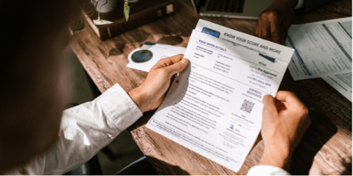 A person is sitting at a table holding a piece of paper.