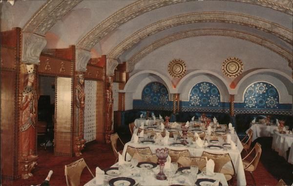 Pink draped stage curtains with gold trim framing a small cityscape set and arched window backdrop