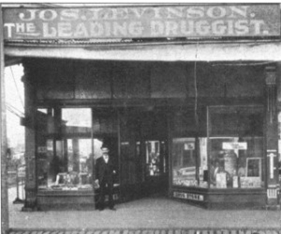 Old storefront of Joseph Levinson's shop with a man (likely Joseph) standing in the entrance under a sign reading 