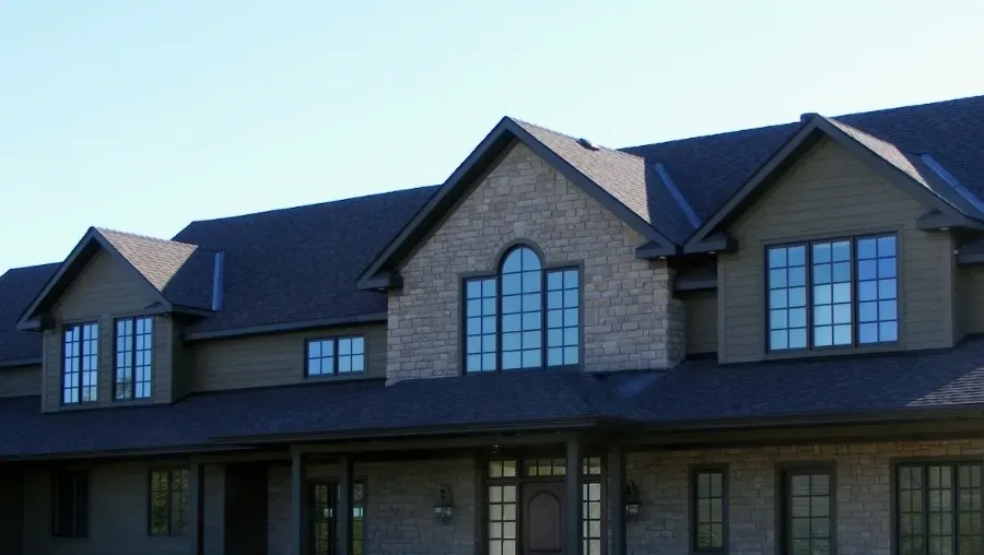 Large stone house with dark roof and arched windows at dusk