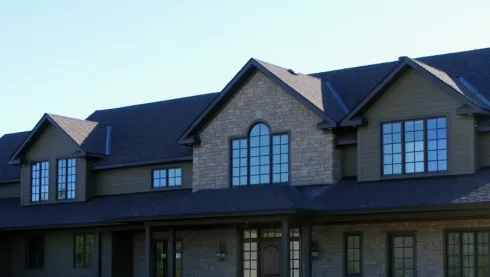 Large stone house with dark roof and arched windows at dusk