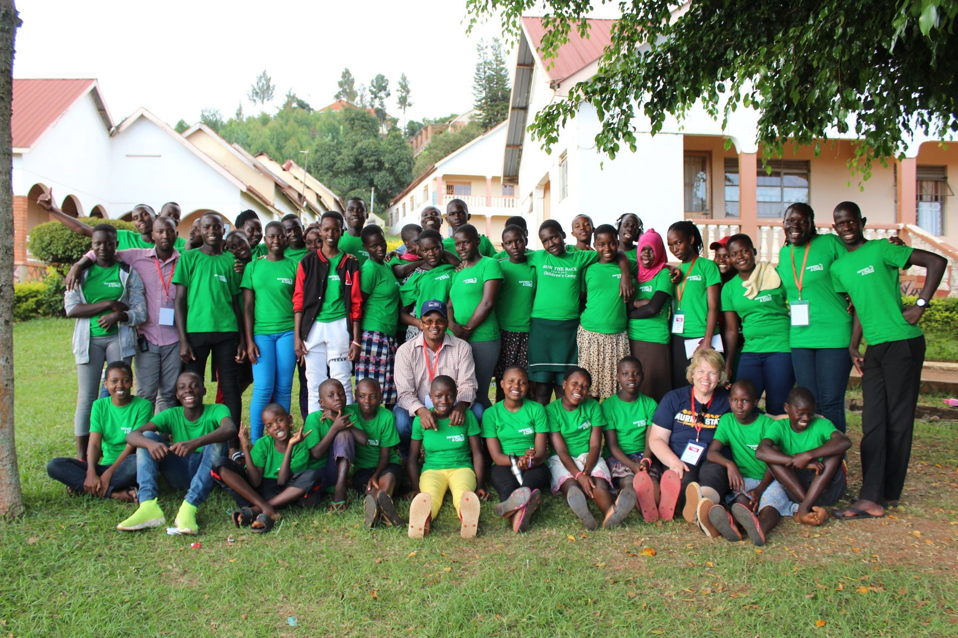 Group of people in green shirts pose outdoors in front of buildings.