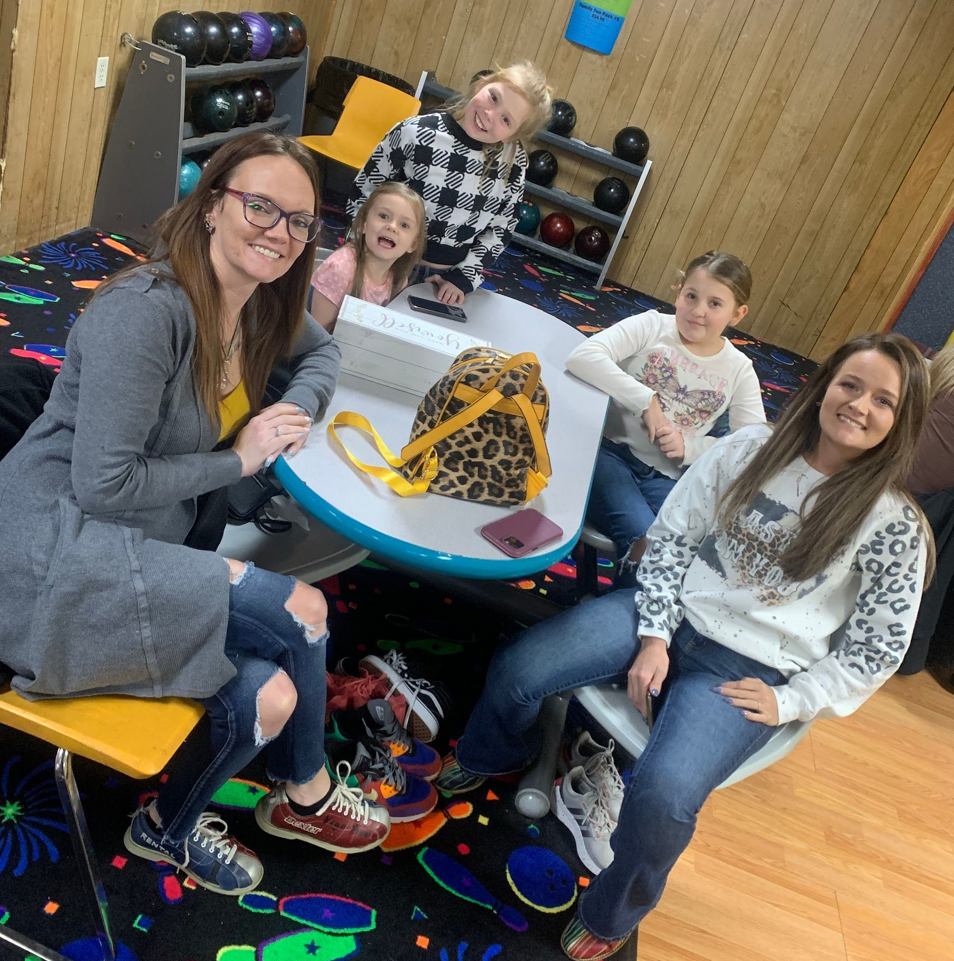 Five people smiling around a table in a colorful playroom with balls and toys.