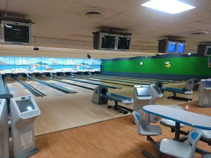 Bowling alley with multiple lanes, screens, and seating.