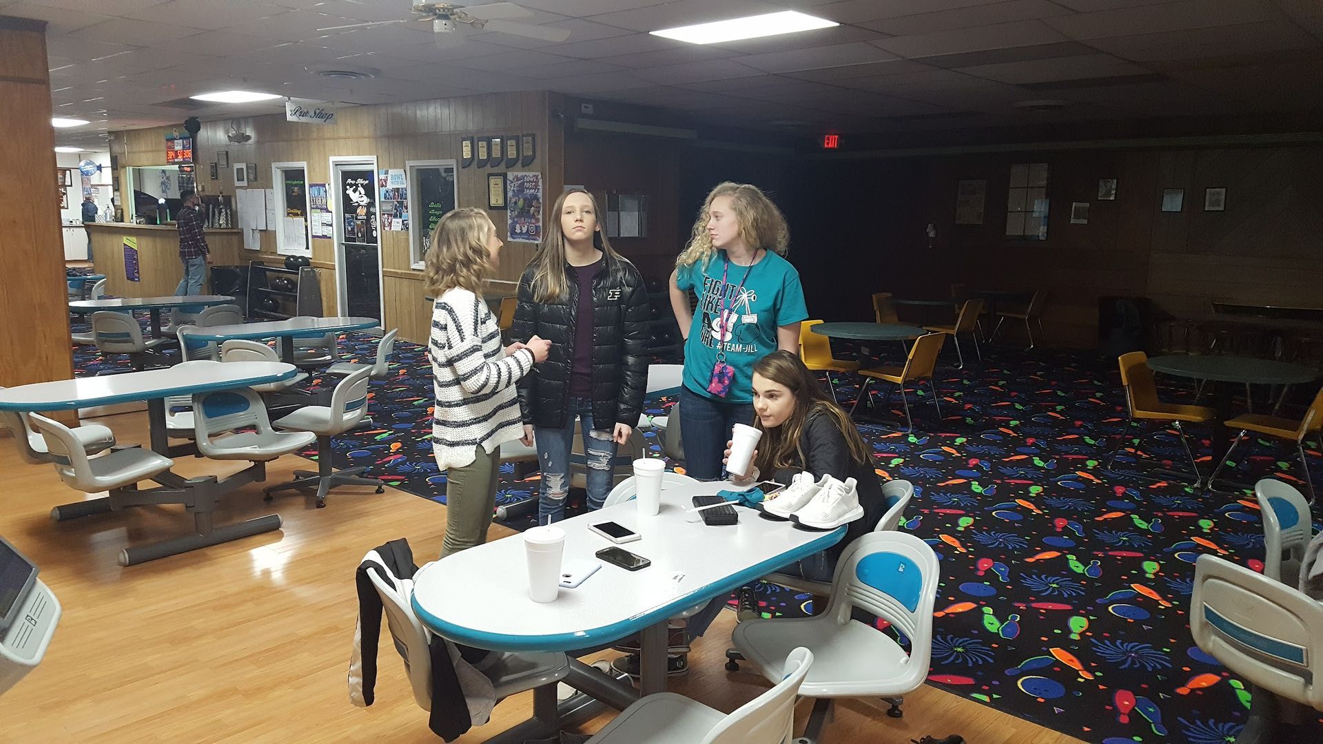 A group of people are standing around a table in a bowling alley.